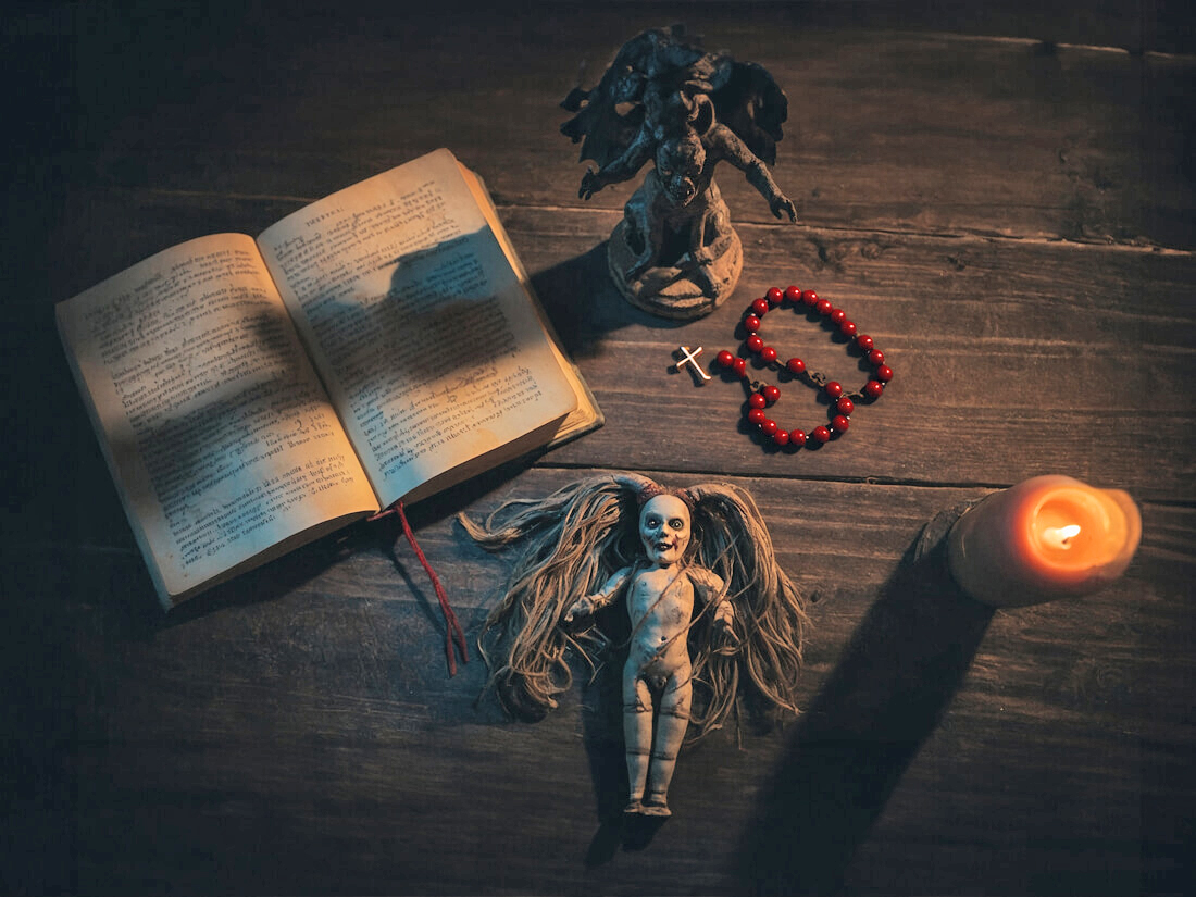 A table with ritual materials, including a devil figurine and a voodoo doll